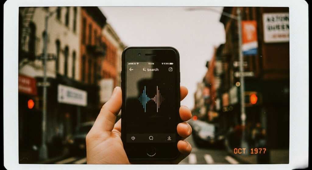 Shaky hand holding phone with voice search in Astoria.